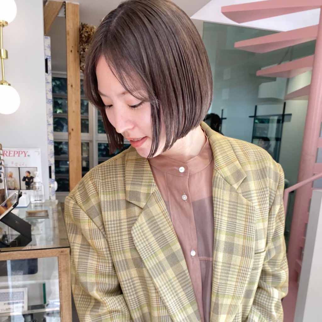 a girl with a bob wolf cut wearing a yellow checkered coat