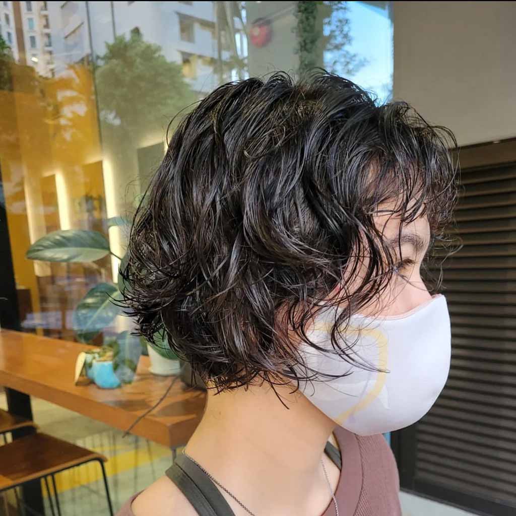 a girl with a curly bob wolf cut wearing a white mask