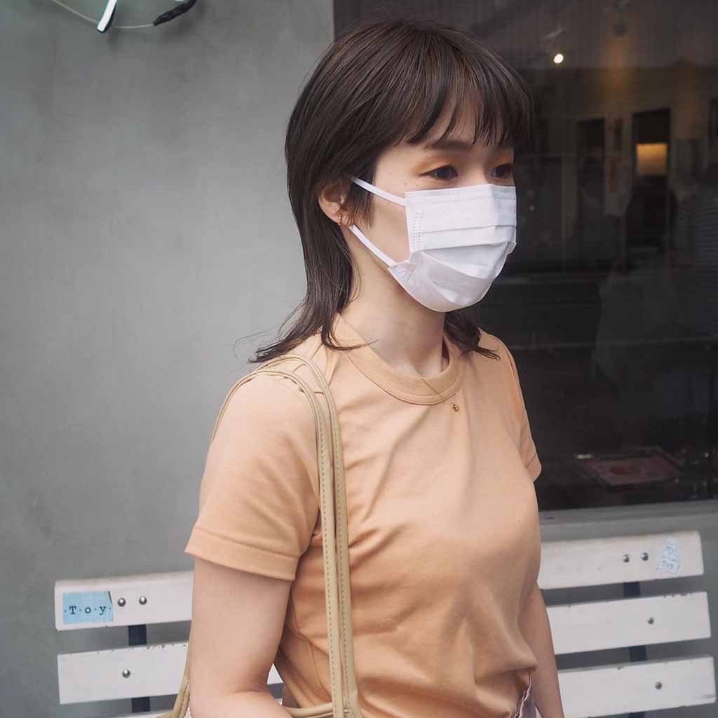 a girl with an elongated bob wolf cut, wearing a mask and a skin color tshirt