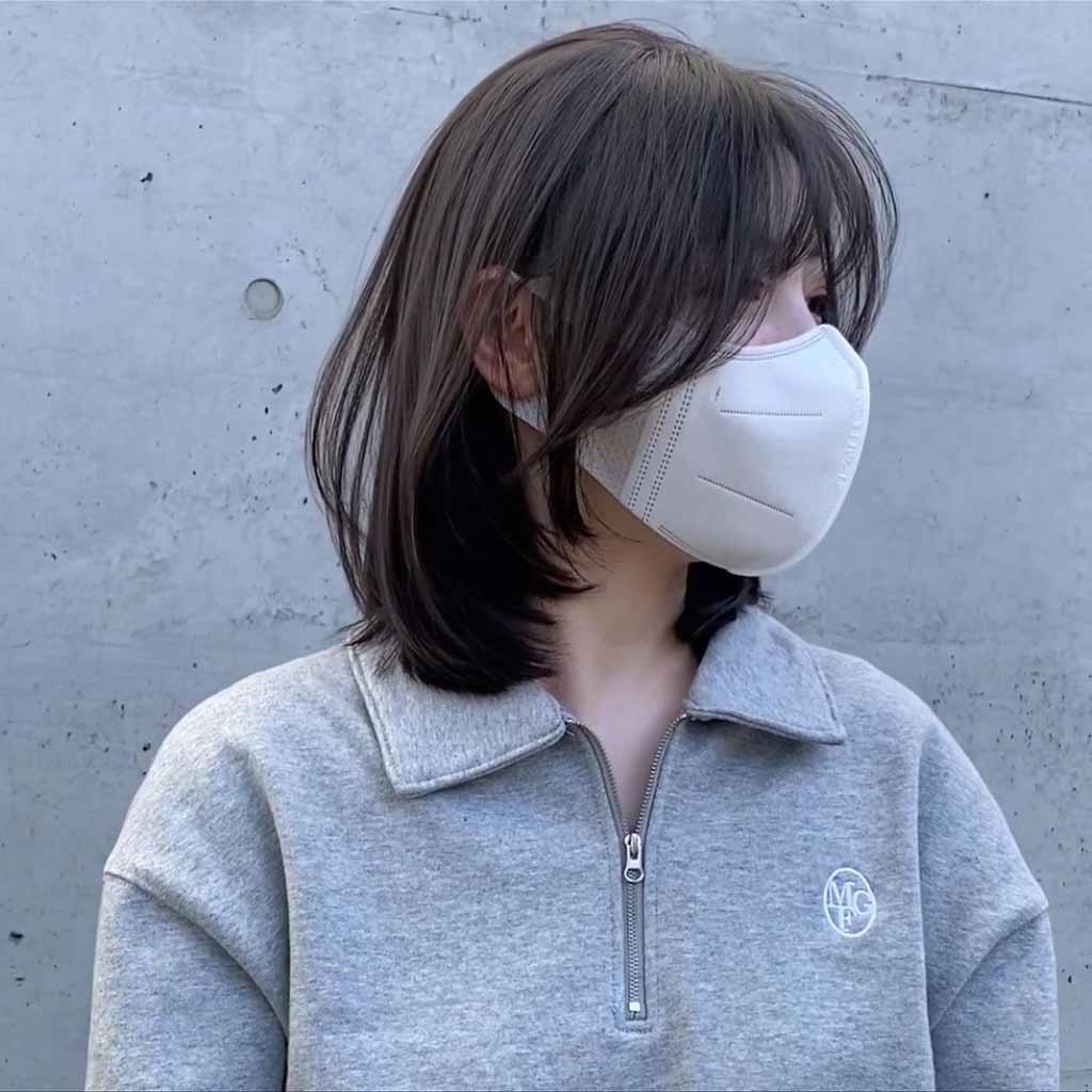 a girl with s bob wolf cut with wispy bangs, wearing a mask and grey sweatshirts