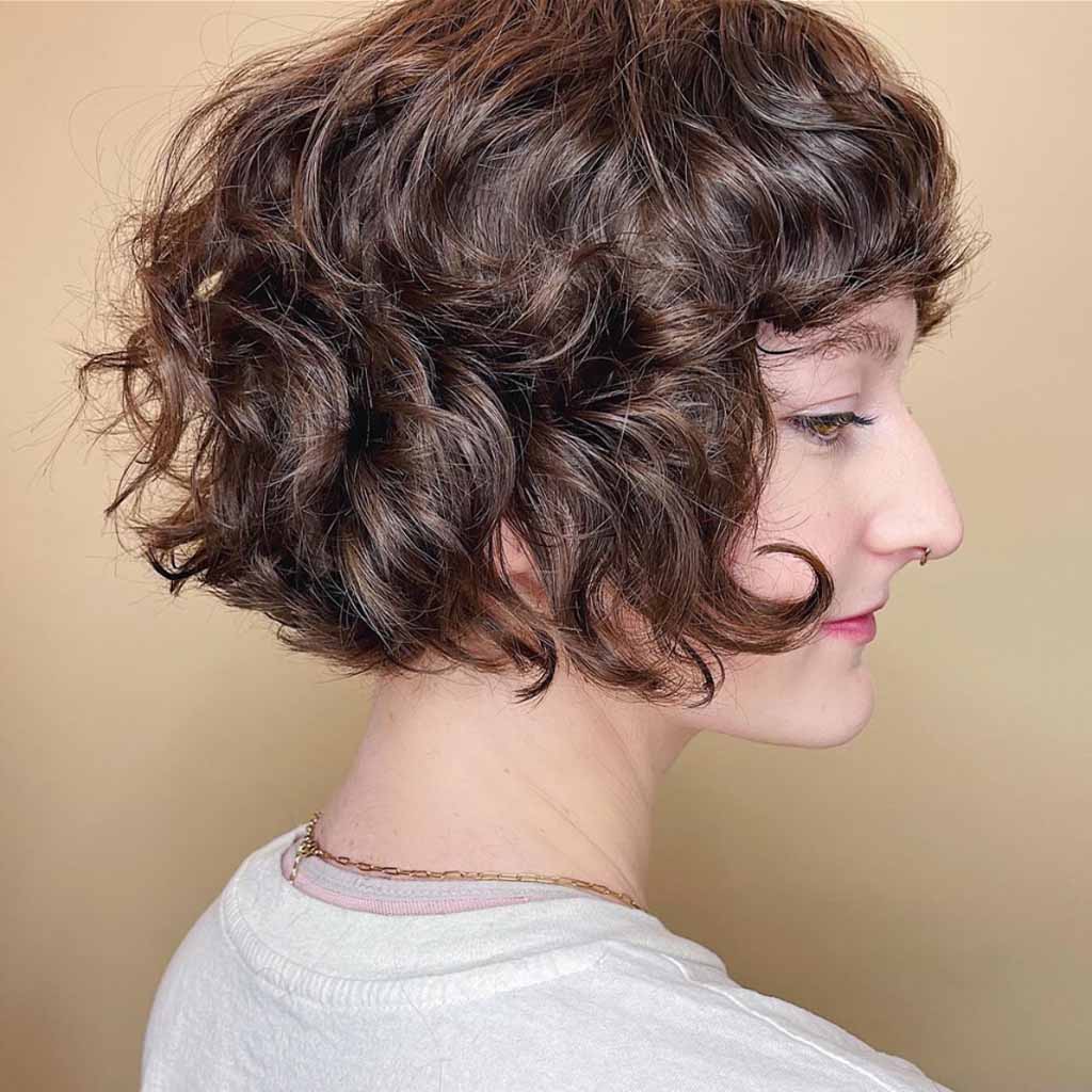 a side shot of a girl with a curly bob wolf cut
